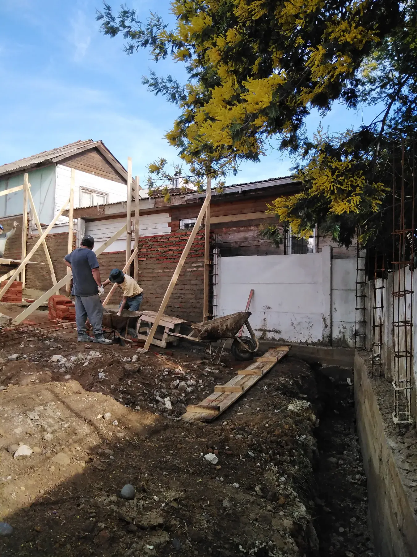Faena activa con albañilería, madera y herramientas de construcción.