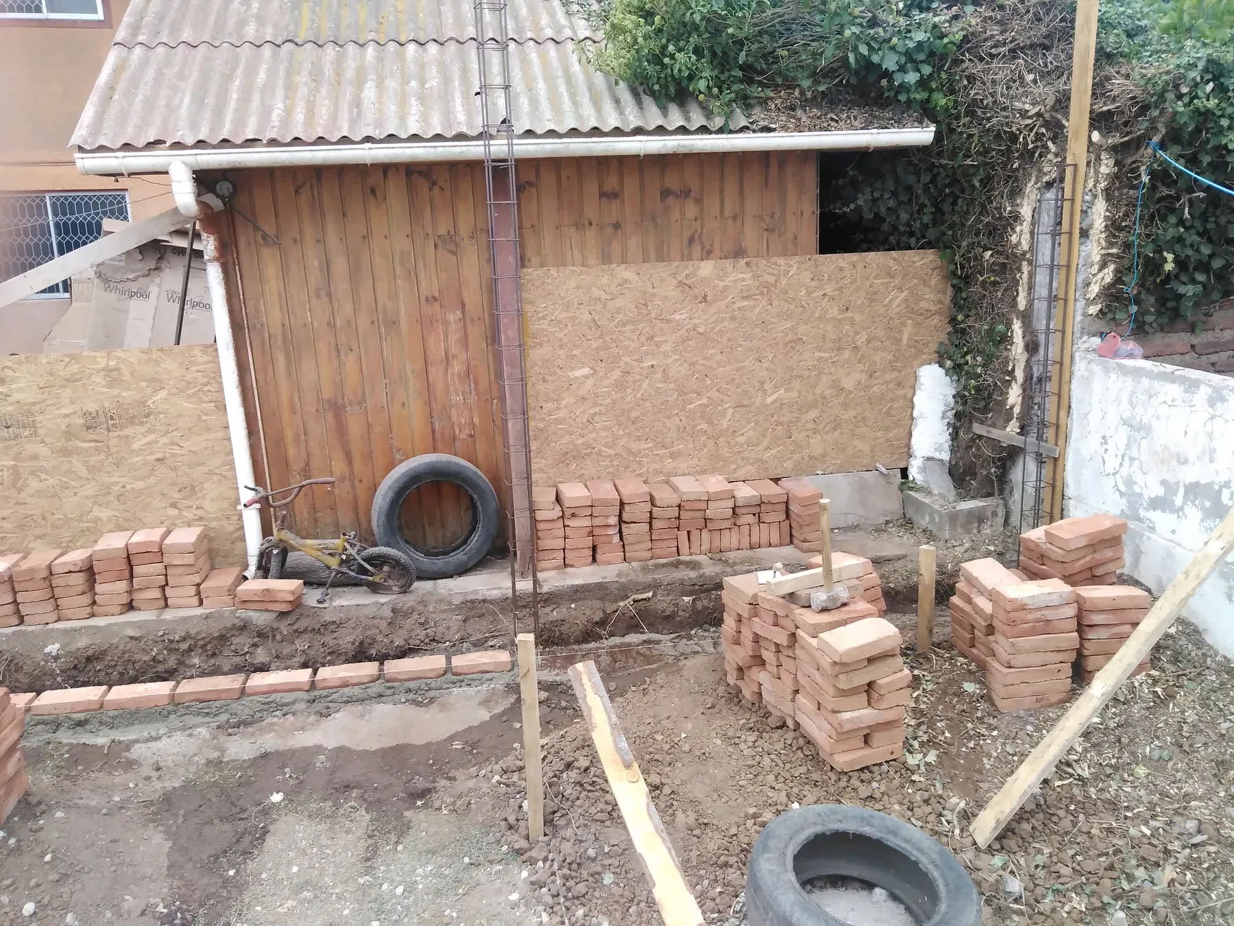 Preparación de fundaciones y armaduras junto a una construcción de madera existente.