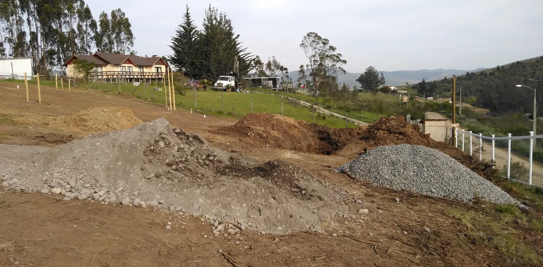 Terreno rural con movimientos de tierra, áridos y viviendas entre lomas.