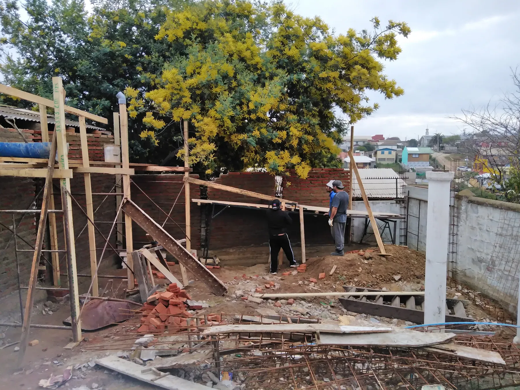 Muros, estructura y vivienda existente visibles durante una ampliación residencial.
