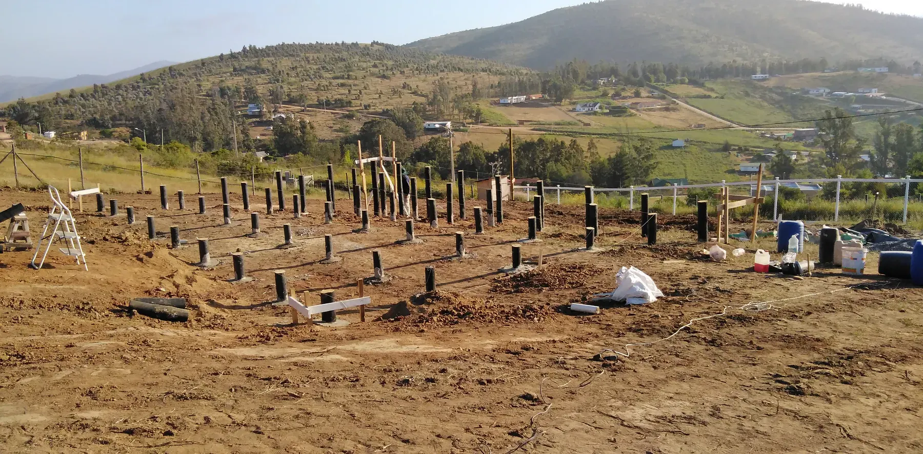 Apoyos de fundación distribuidos sobre un terreno rural en pendiente.