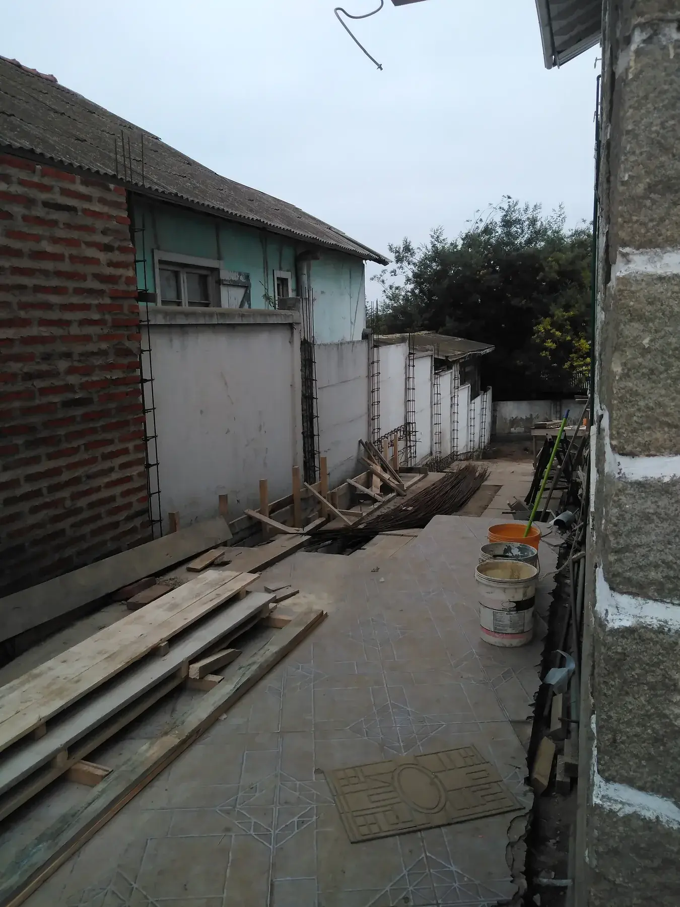 Pasaje longitudinal entre viviendas con armaduras, materiales y faena en ejecución.