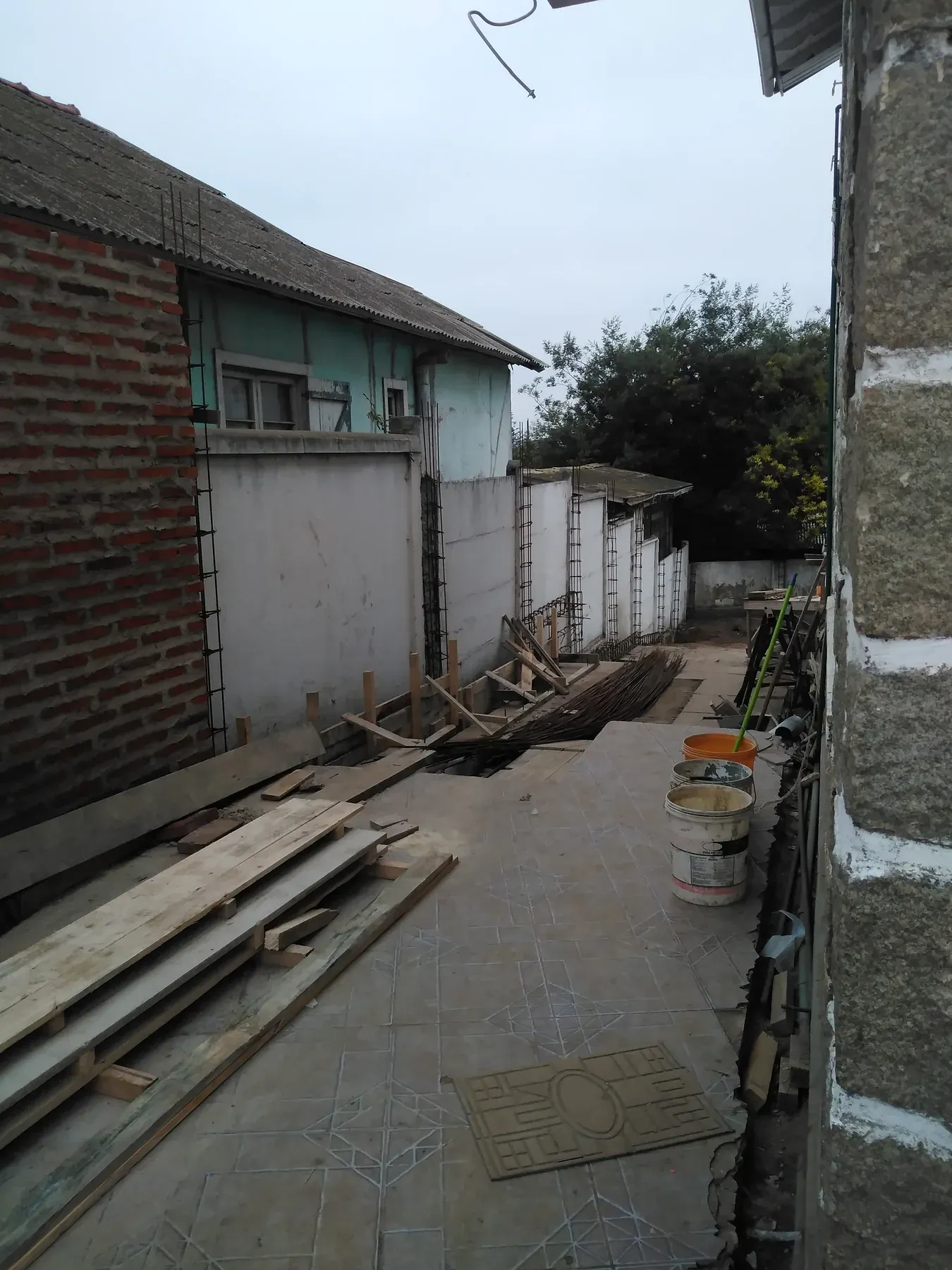 Pasaje longitudinal entre viviendas con armaduras, materiales y faena en ejecución.