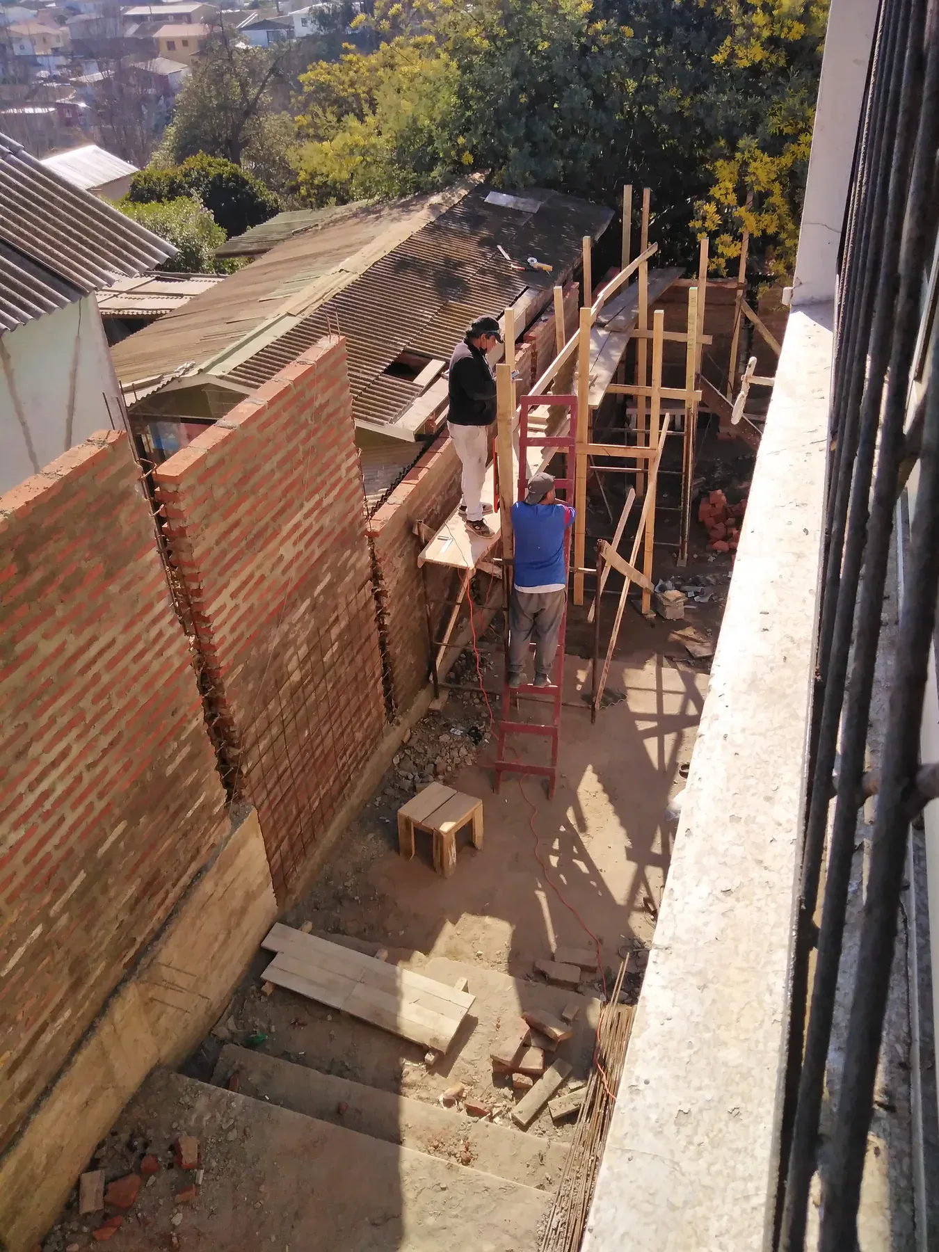 Muro de ladrillo y refuerzos verticales en proceso de construcción.