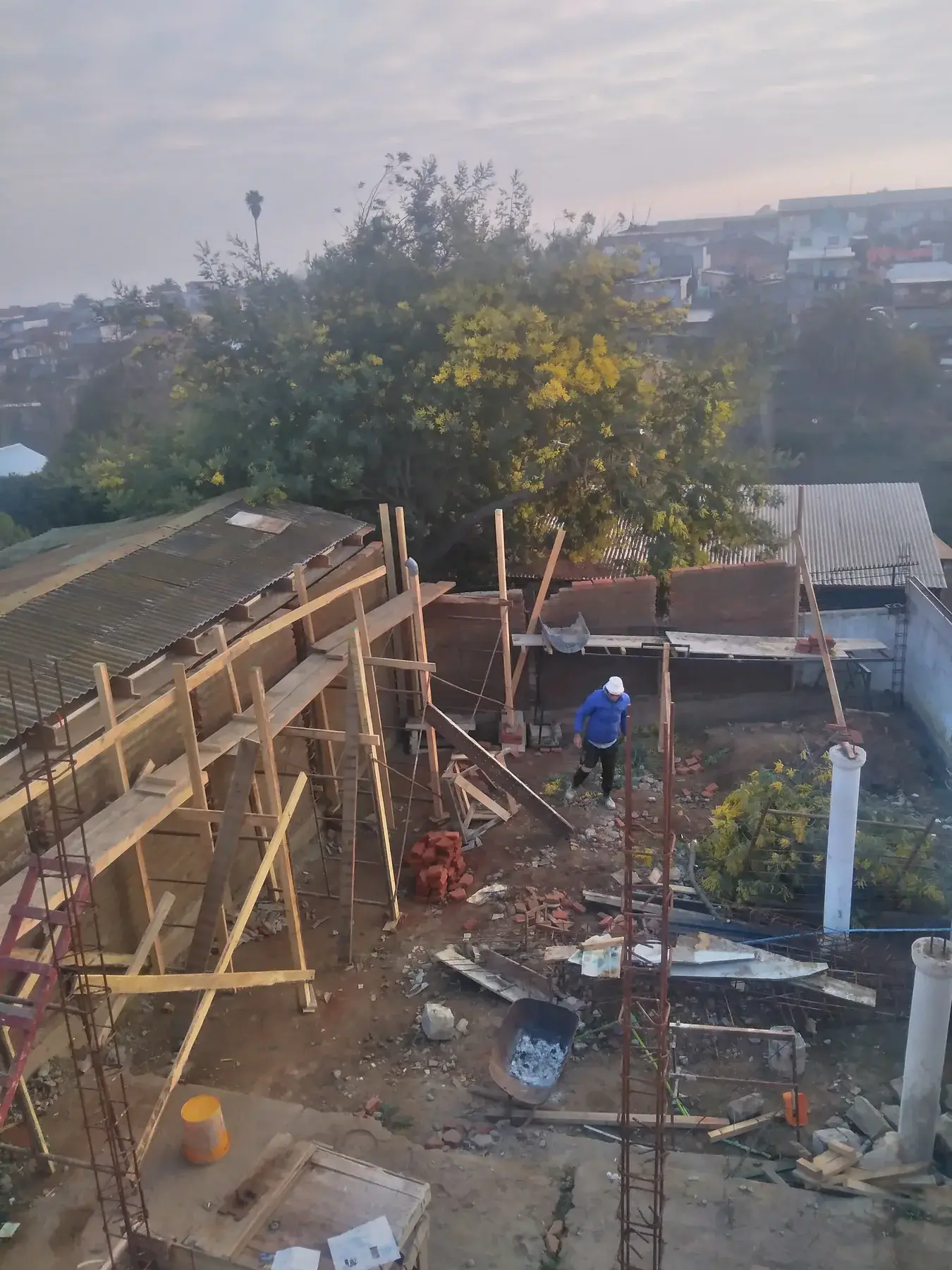 Vista panorámica de una faena con moldajes de madera y construcciones vecinas.