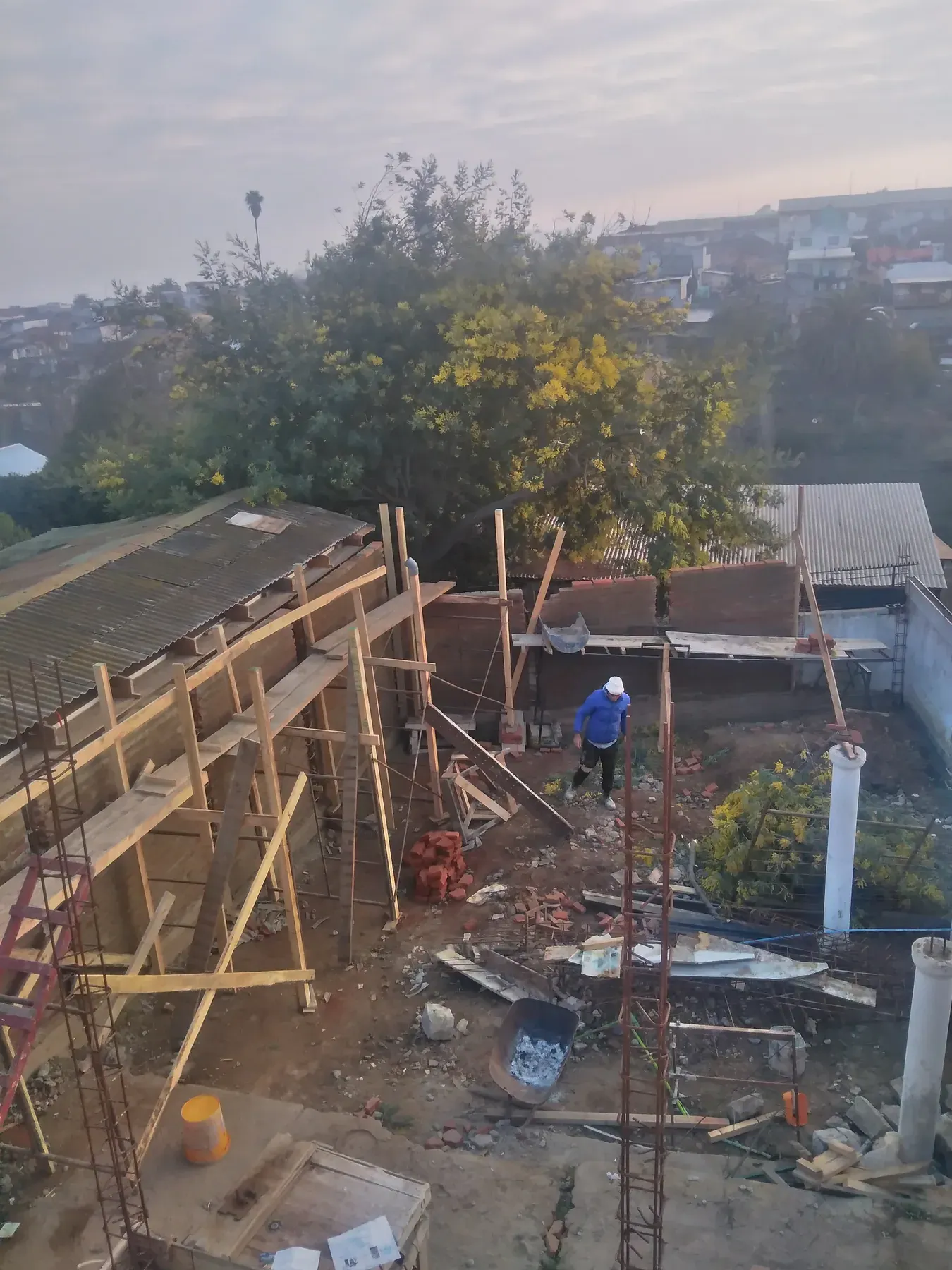 Vista panorámica de una faena con moldajes de madera y construcciones vecinas.