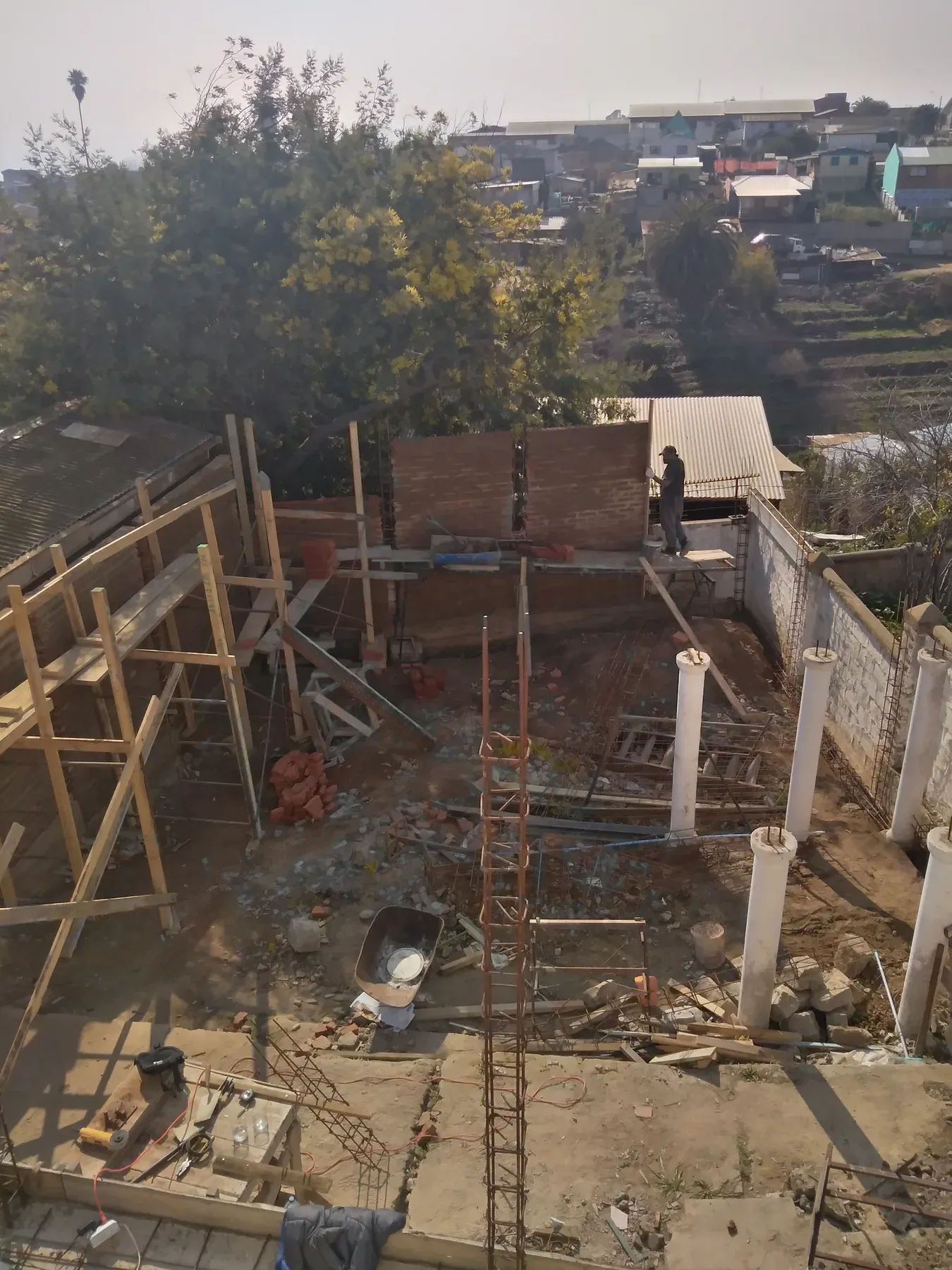 Recinto en obra con muros, armaduras y tuberías visibles desde arriba.