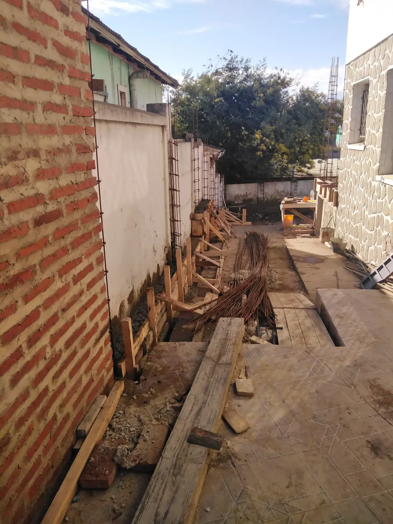 Muro de albañilería y estructura en ejecución entre construcciones existentes.