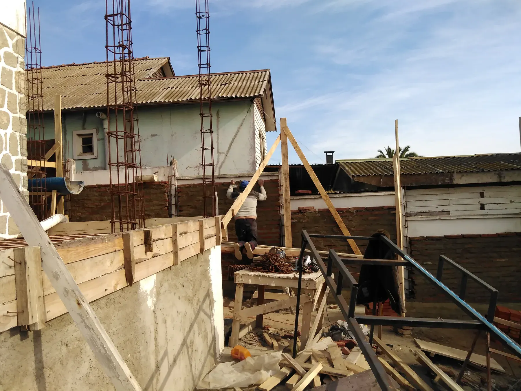 Muro de ladrillo, puntales y estructura de madera en obra.